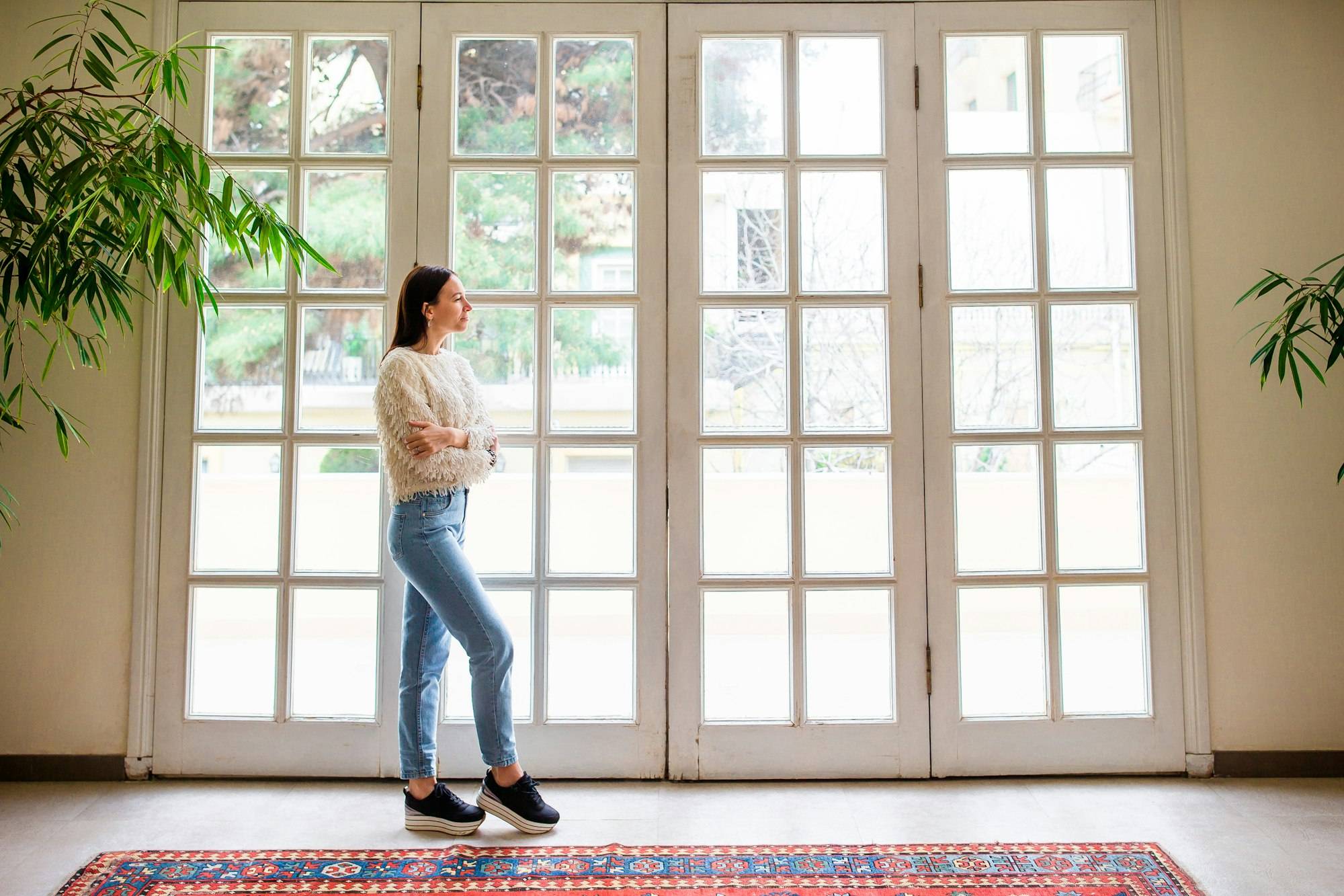 Beautiful girl on the terrace looks in a large window in a cozy boutique hotel