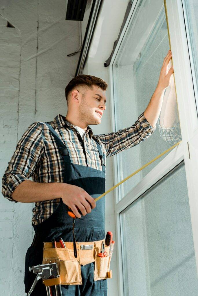 installer standing near windows and holding measuring tape