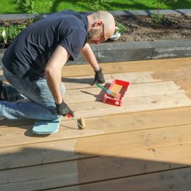 Husband paints the wooden deck in the backyard.